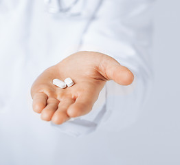 Image showing doctor hands giving white pills 
