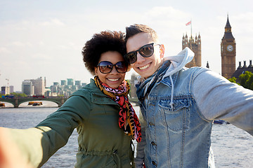 Image showing happy teenage couple taking selfie in london city