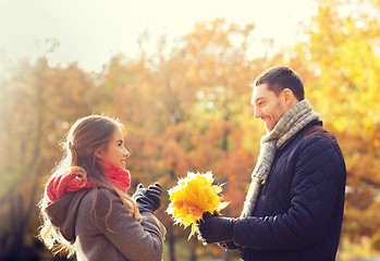 Image showing smiling couple with bunch of leaves in autumn park