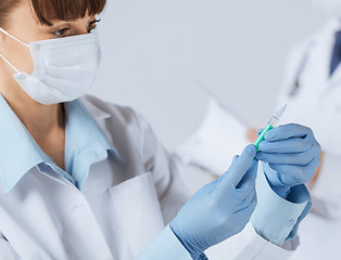 Image showing female doctor holding syringe with injection