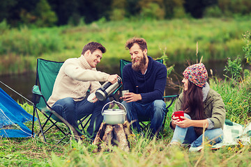 Image showing group of smiling tourists cooking food in camping