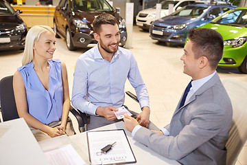 Image showing happy couple with car dealer in auto show or salon