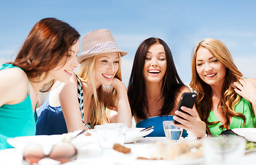 Image showing girls looking at smartphone in cafe on the beach