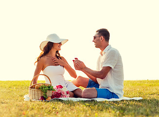 Image showing smiling couple with small red gift box on picnic