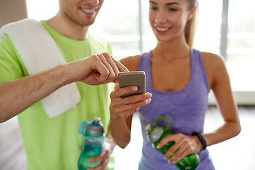 Image showing happy woman and trainer showing smartphone in gym
