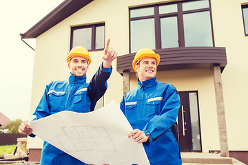 Image showing smiling builders with blueprint pointing finger