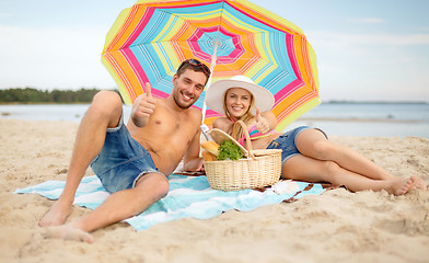 Image showing couple having picnic and sunbathing on beach