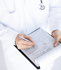 Image showing male doctor holding prescription paper in hand