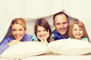 Image showing happy family with two kids under blanket at home