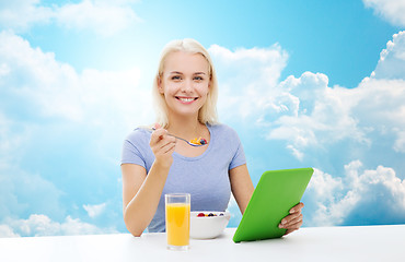 Image showing smiling woman with tablet pc eating breakfast