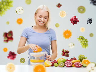 Image showing smiling woman squeezing fruit juice at home