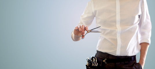 Image showing close up of male stylist with scissors over blue