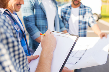 Image showing close up of builders with clipboard and blueprint