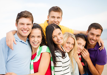 Image showing group of happy friends hugging on beach