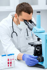 Image showing young scientist looking to microscope in lab