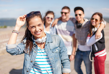 Image showing teenage girl with headphones and friends outside