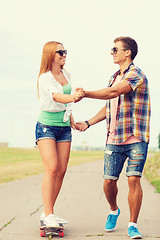 Image showing smiling couple with skateboard outdoors