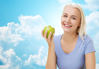 Image showing happy woman eating green apple over sky