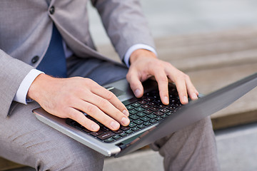 Image showing close up of business man with laptop in city