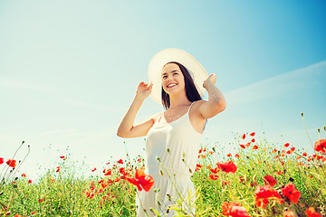 Image showing smiling young woman in straw hat on poppy field