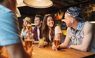 Image showing happy friends with drinks talking at bar or pub