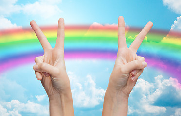 Image showing hands showing peace sign over rainbow in sky