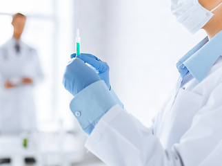 Image showing female doctor holding syringe with injection