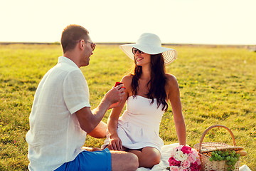 Image showing smiling couple with small red gift box on picnic