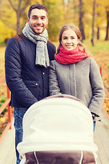 Image showing smiling couple with baby pram in autumn park