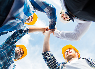 Image showing close up of builders in hardhats making high five