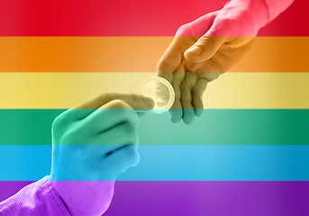 Image showing close up of male gay couple hands giving condom