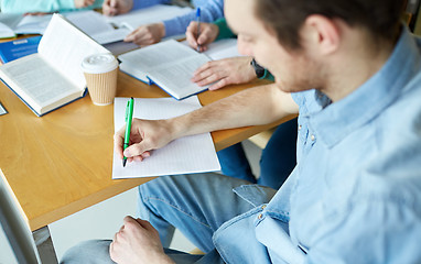 Image showing happy students writing to notebooks in library