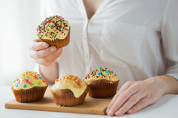 Image showing close up of woman with glazed cupcakes or muffins