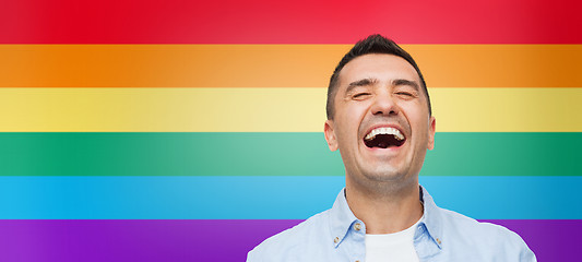 Image showing laughing man over rainbow flag stripes background