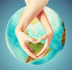 Image showing human hands showing heart shape over earth globe