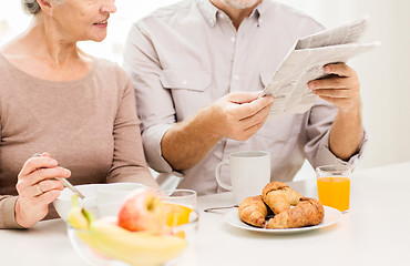 Image showing happy senior couple reading newspaper at breakfast