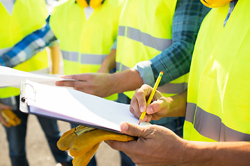 Image showing close up of builders in vests writing to clipboard