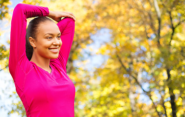 Image showing smiling african woman stretching hand outdoors