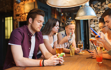 Image showing friends with smartphones and drinks at bar