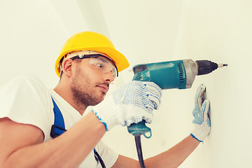 Image showing builder in hardhat working with drill indoors