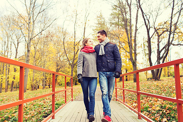 Image showing smiling couple hugging on bridge in autumn park