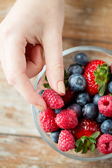 Image showing close up of woman hands with berries in glass bowl