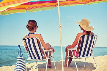 Image showing happy women sunbathing in lounges on beach