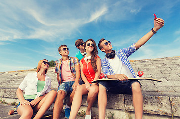 Image showing group of smiling friends with smartphone outdoors