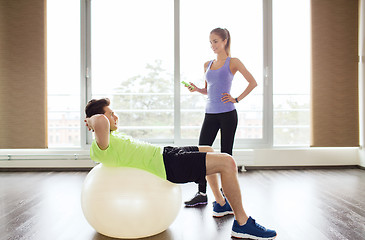 Image showing smiling man and woman with exercise ball in gym