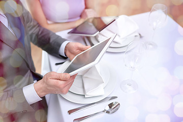 Image showing close up of couple with tablet pc at restaurant