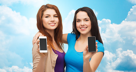 Image showing happy young women showing smartphones screens