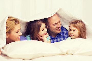 Image showing happy family with two kids under blanket at home