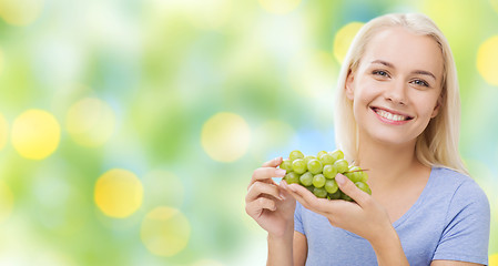 Image showing happy woman eating grapes
