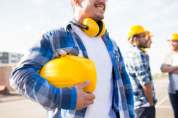 Image showing close up of builder holding hardhat at building